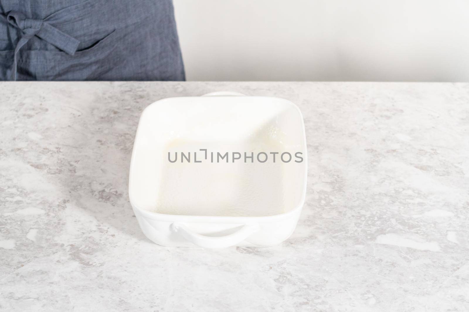 Greasing white casserole dish to bake bread pudding.