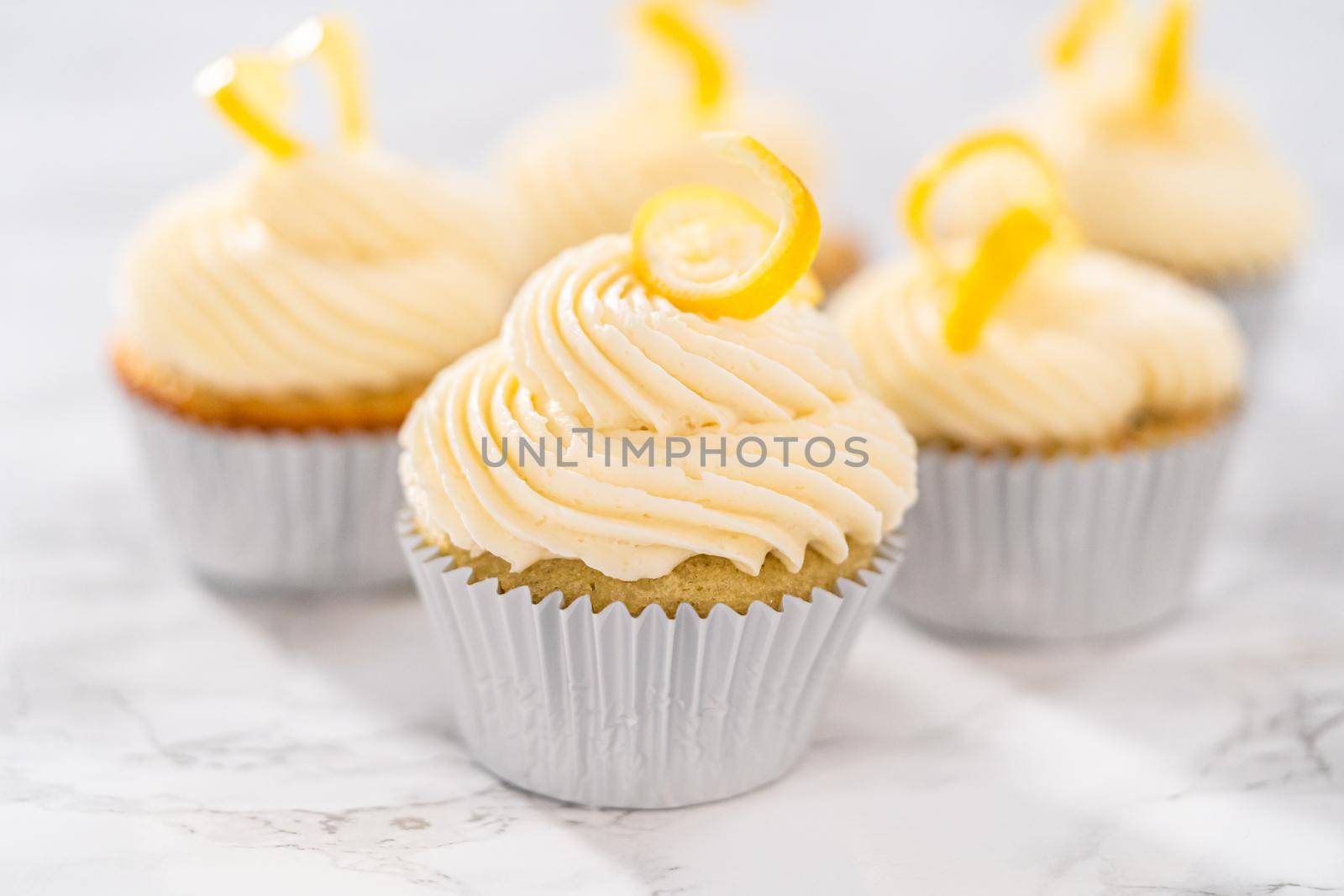 Lemon cupcakes with lemon buttercream frosting, and decorated with lemon swist.