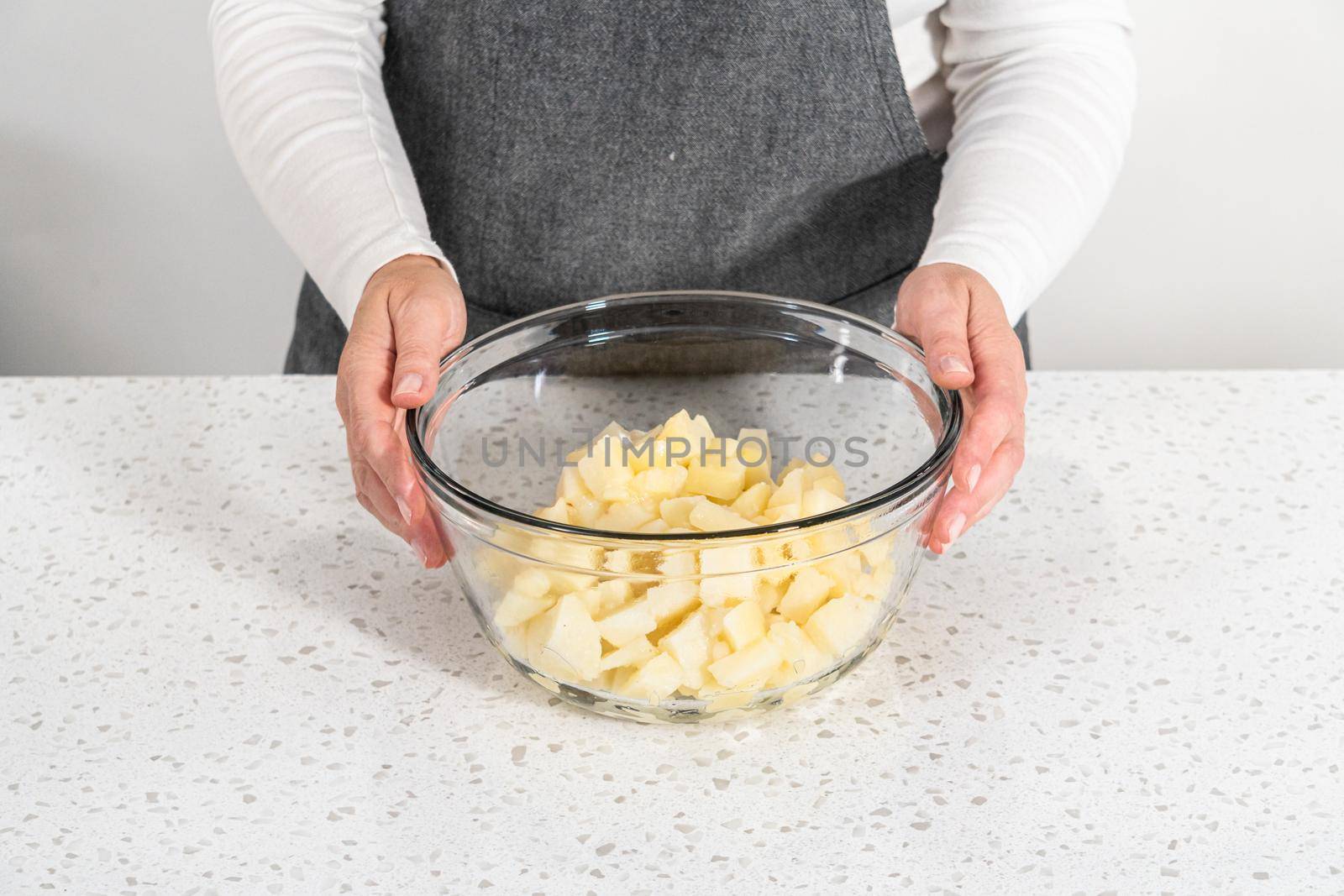 Mixing ingredients in a large glass mixing bowl to make potato salad.