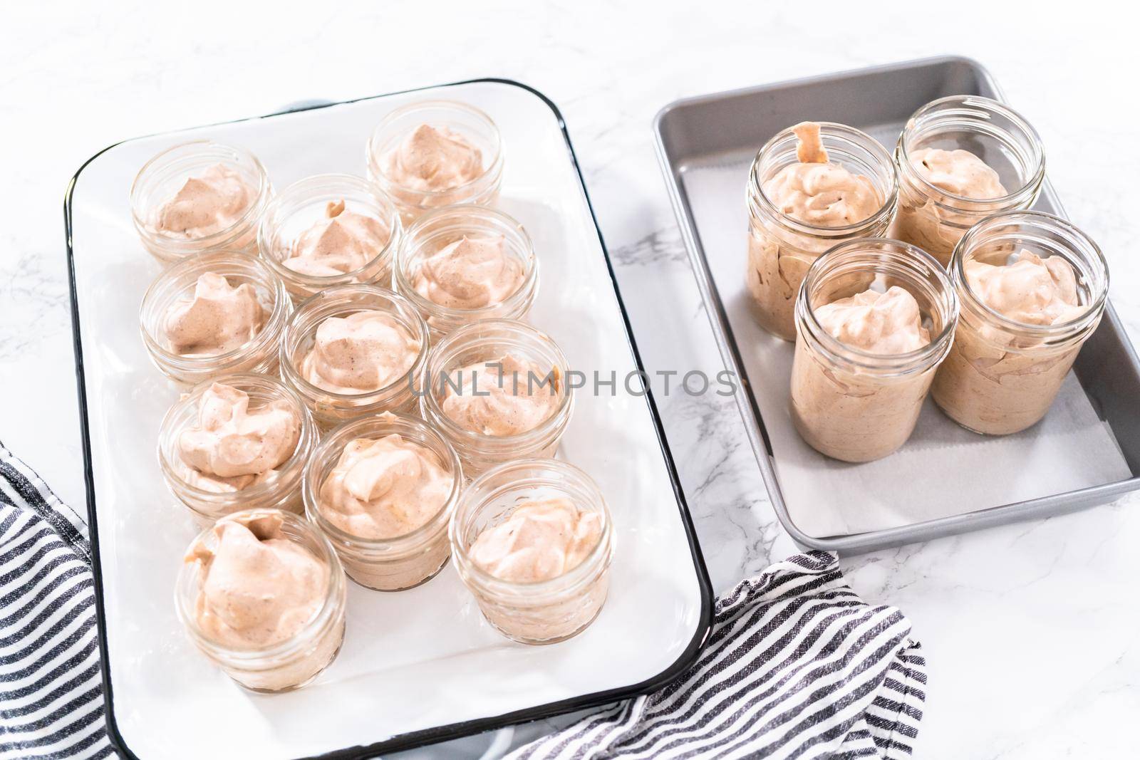 Scooping mixture into the small glass jars to make homemade chocolate ice cream.