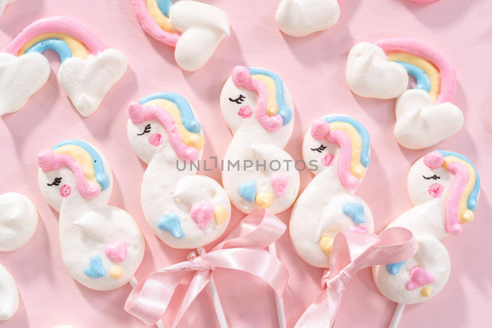 Gourmet unicorn theme meringue pops on a pink background.