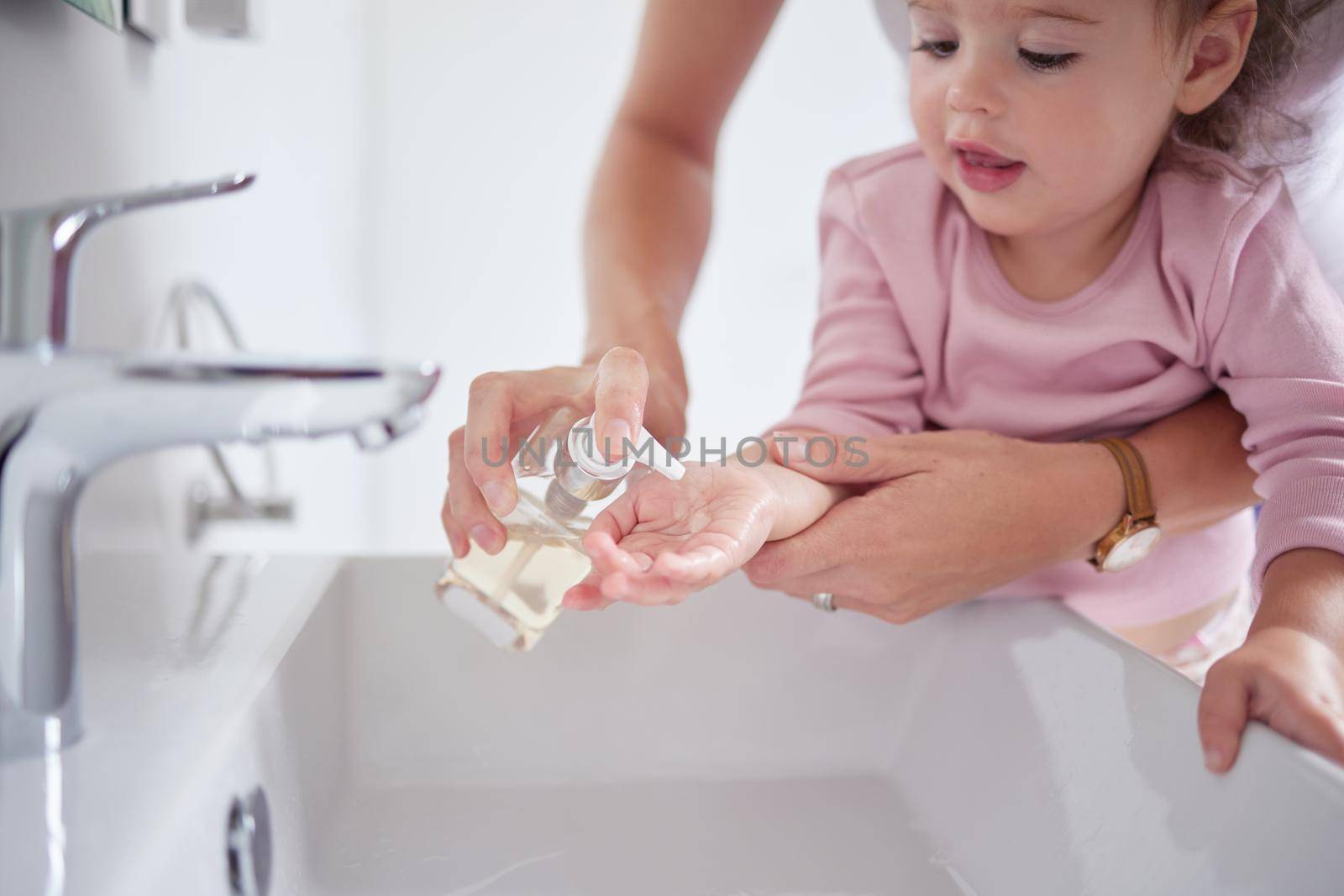 Mother cleaning kids hands with sanitizer liquid soap after baby toddler had dirty fingers in the sink. Healthy, grooming and mom cleaning and helping a young girl with hygiene wellness at home by YuriArcurs