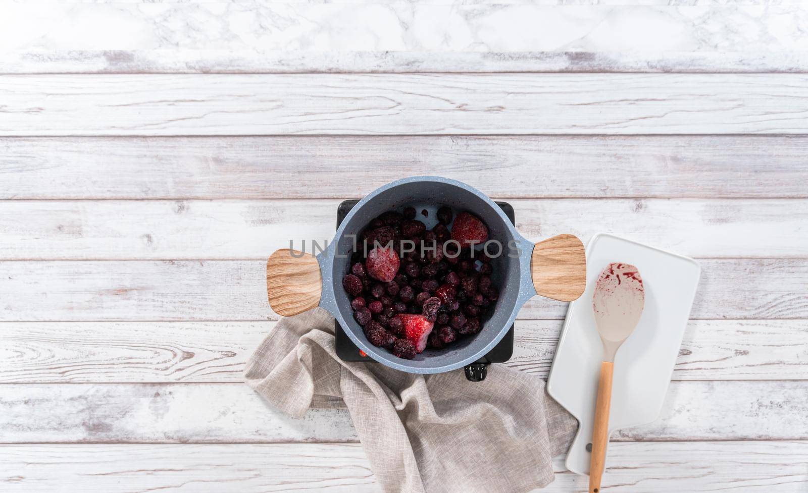 Flat lay. Preparing mixed berry compote from frozen berries in a nonstick cooking pot.