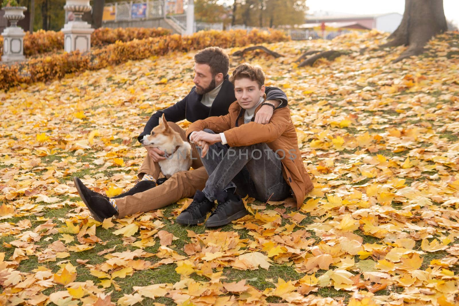 Father and son with a pet on a walk in the autumn park.