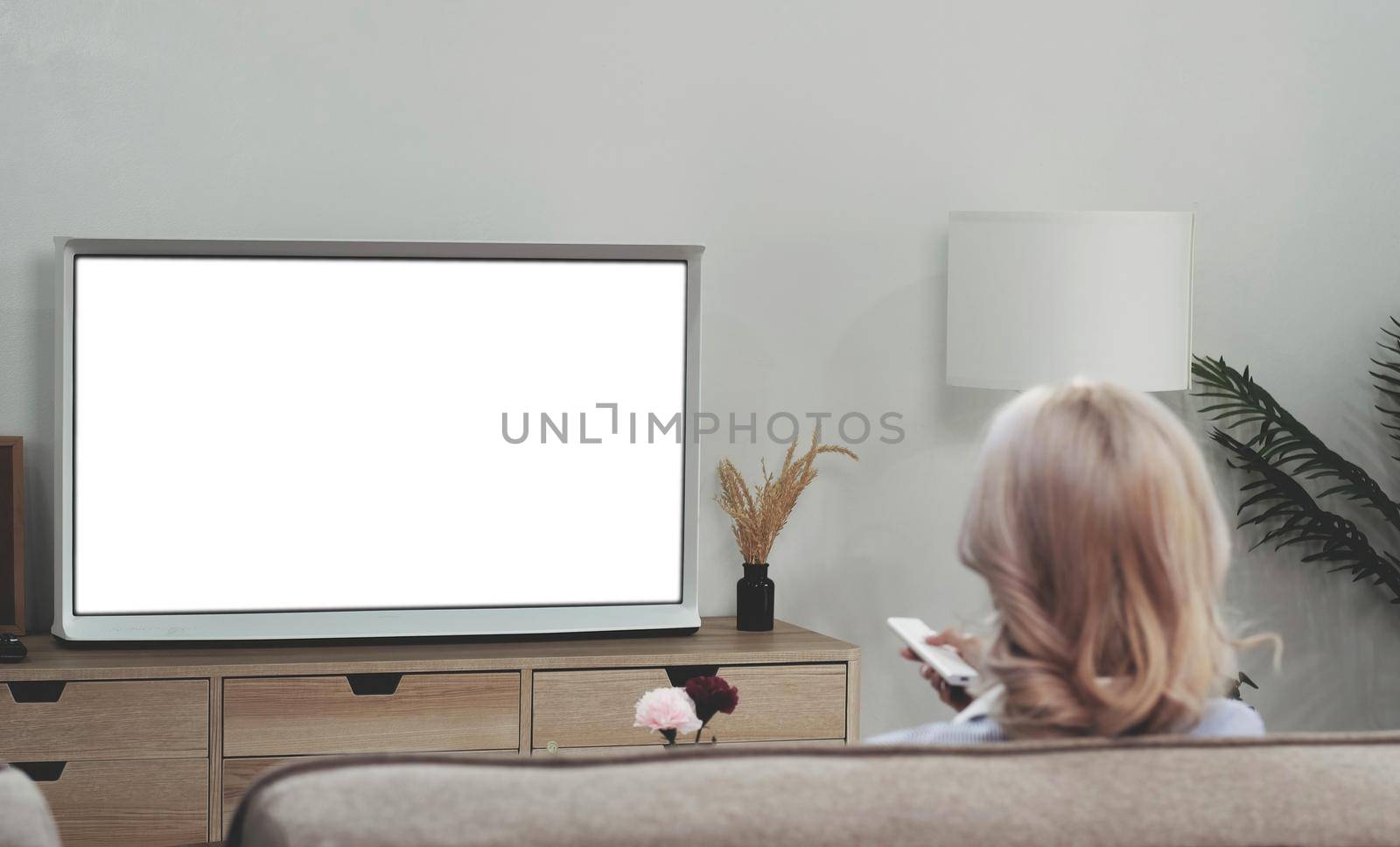 behind of asian young woman watching white screen TV on the sofa at home by wichayada