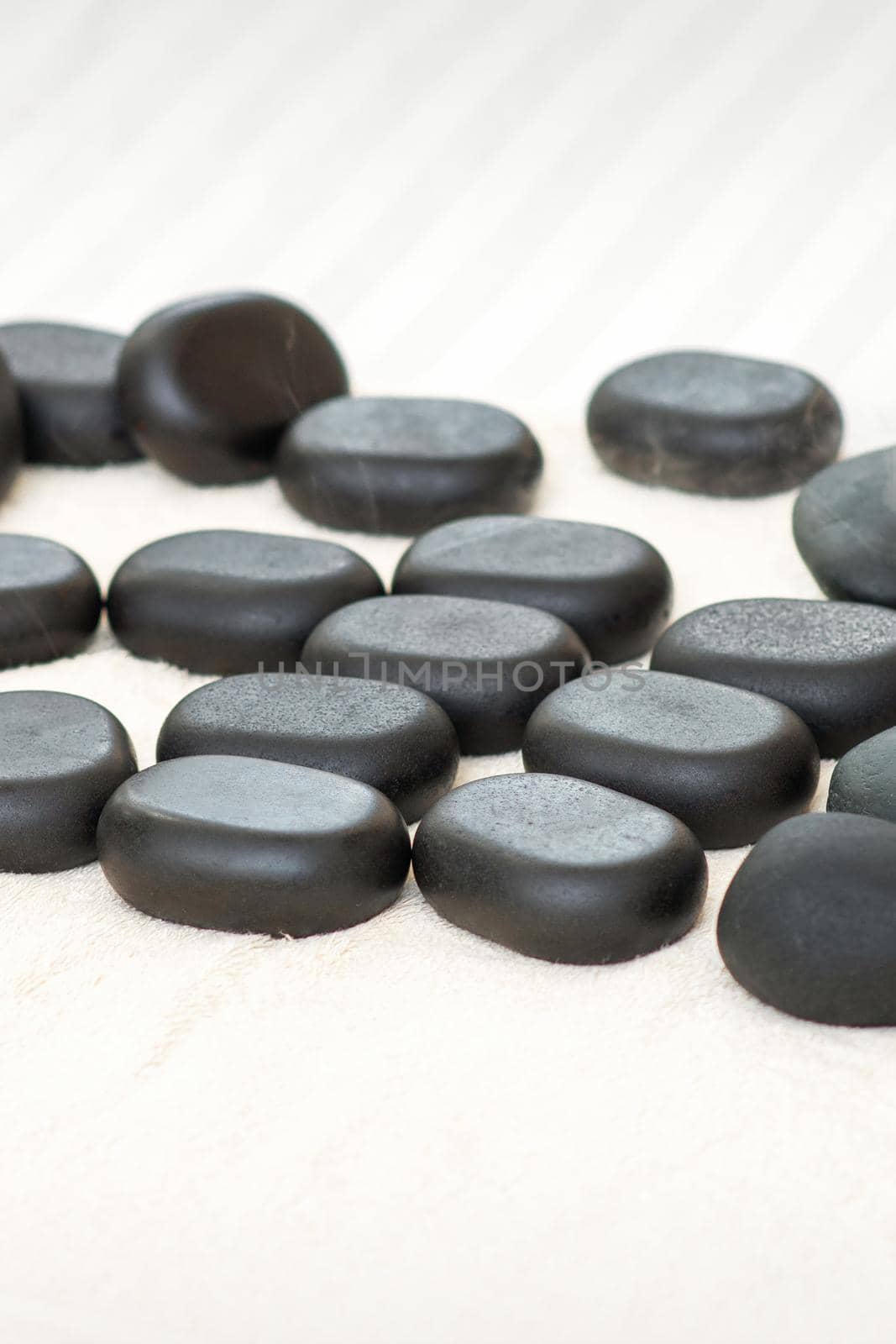 Many black massage stones lying isolated on the towel on the table