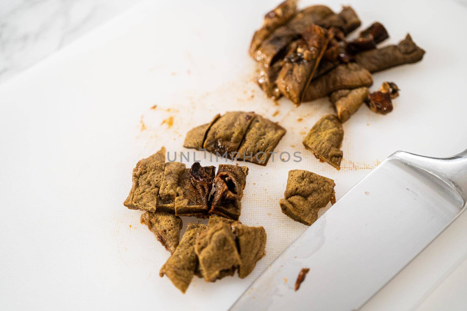 Cutting dehydrated wild mushrooms on a white cutting board.