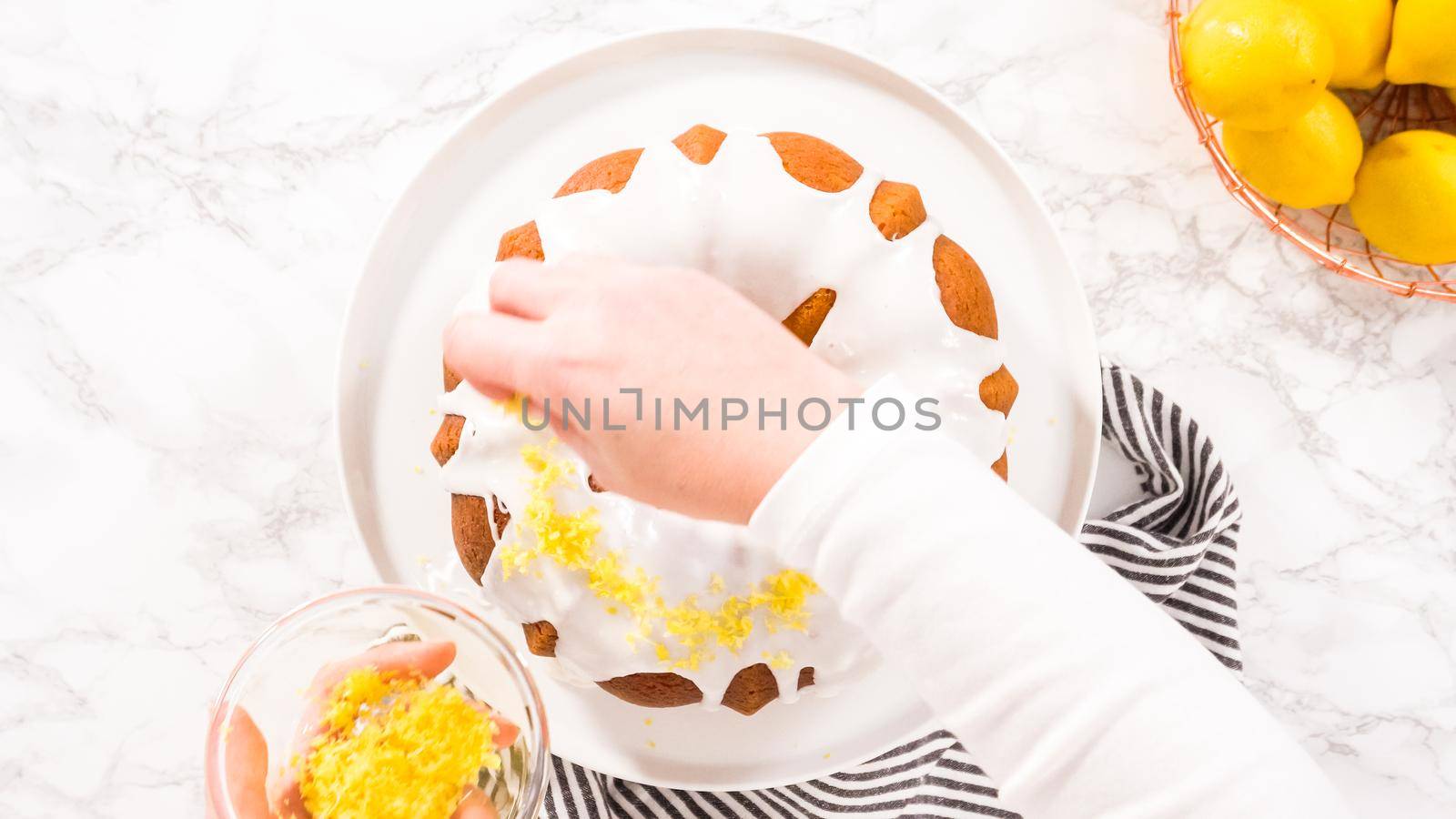 Flat lay. Step by step. Garnishing lemon bundt cake with lemon zest on top of the white glaze.