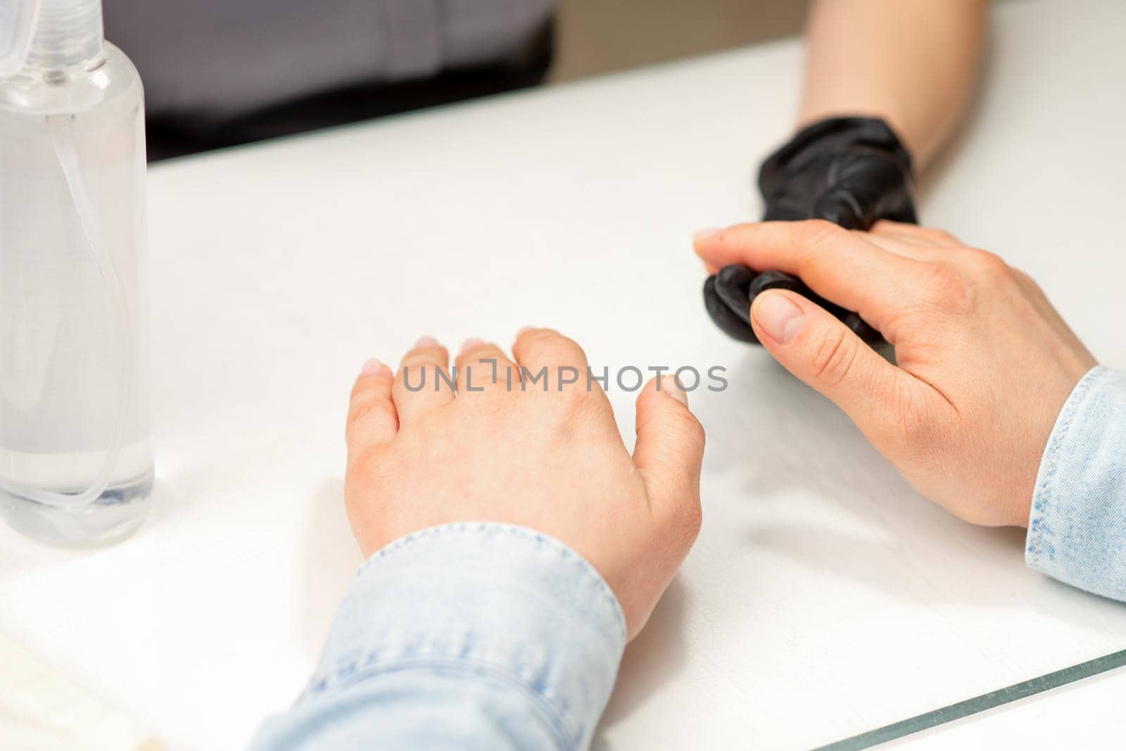 Closeup of manicure master prepares hands of a young woman for manicure procedures