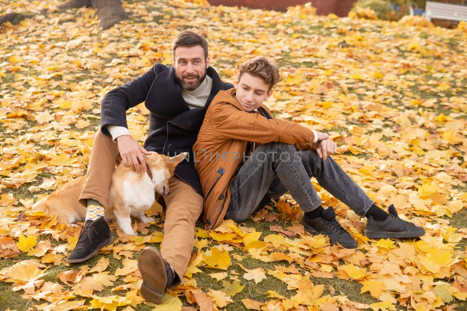 Father and son with a pet on a walk in the autumn park.