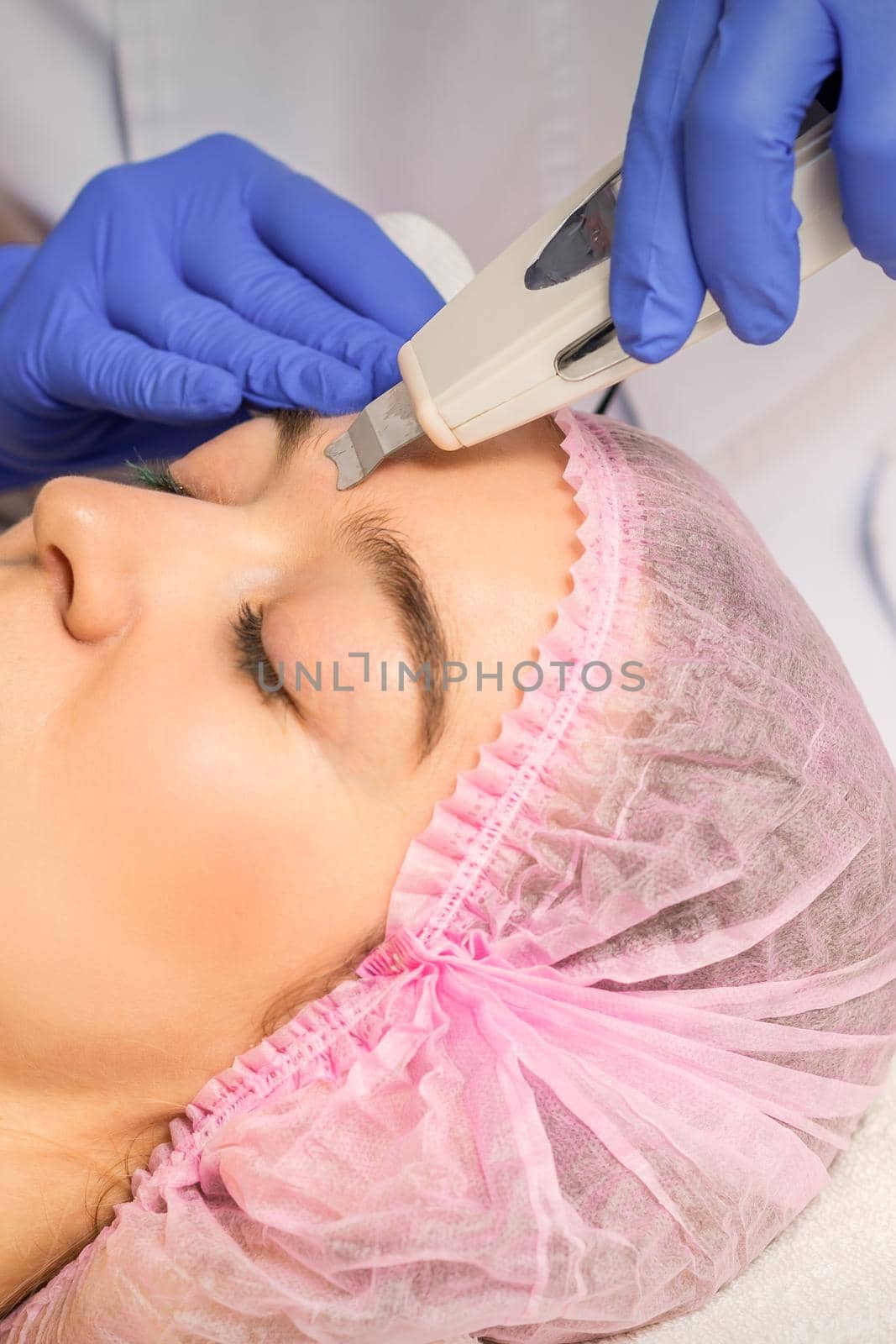 Young caucasian woman having ultrasonic peeling with ultrasound device in a cosmetic beauty salon