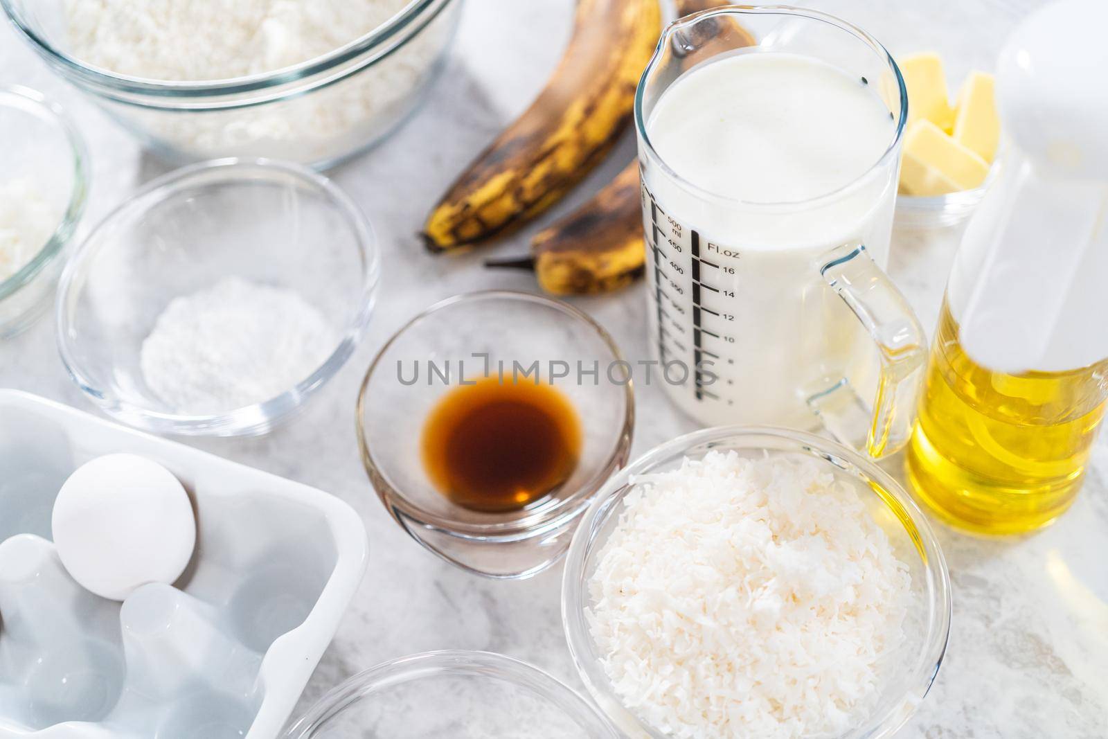 Measured ingredients in glass mixing bowls to prepare coconut banana pancakes for breakfast.