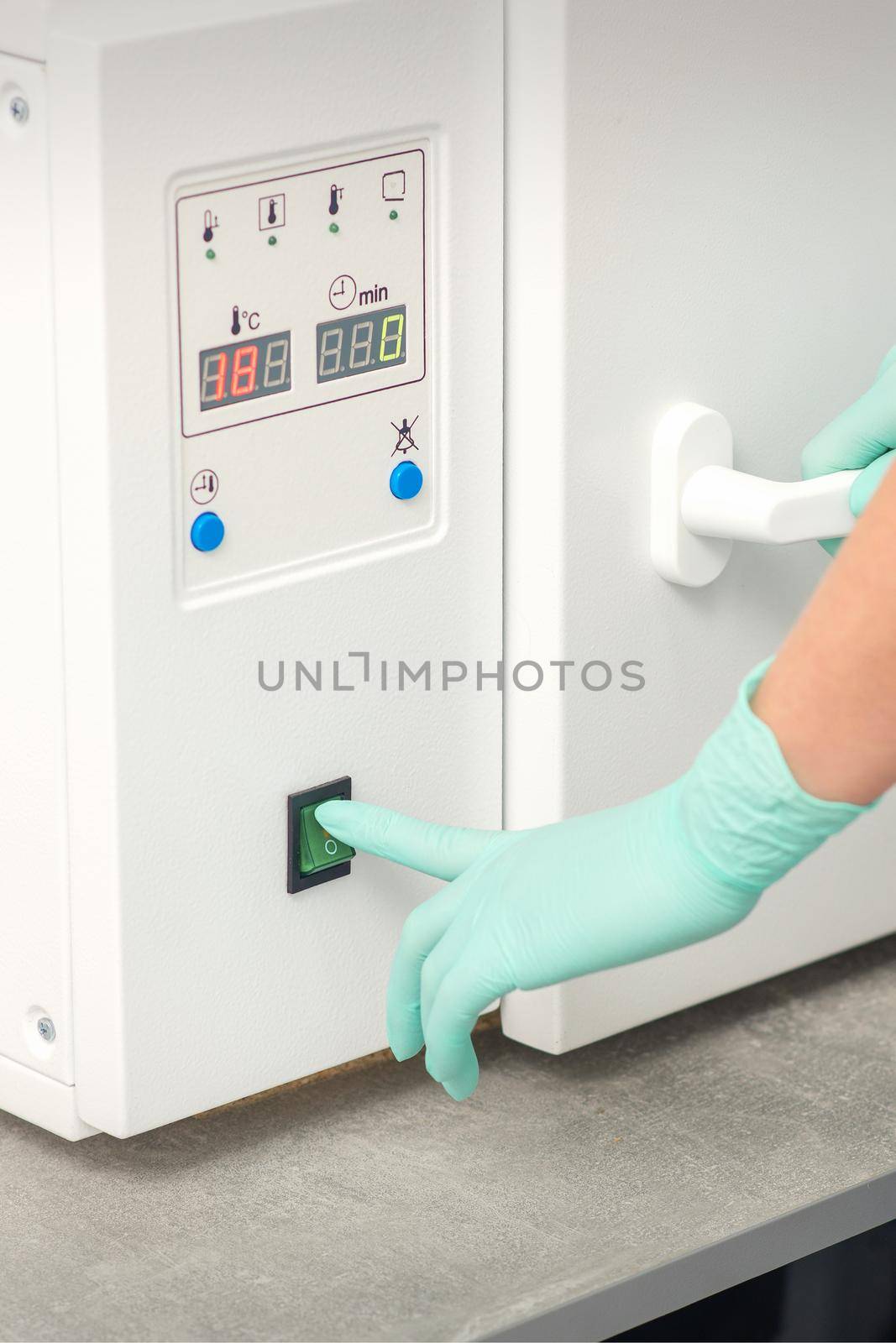 Beautician in protective gloves starts the machine for disinfection of tools before the depilation procedure