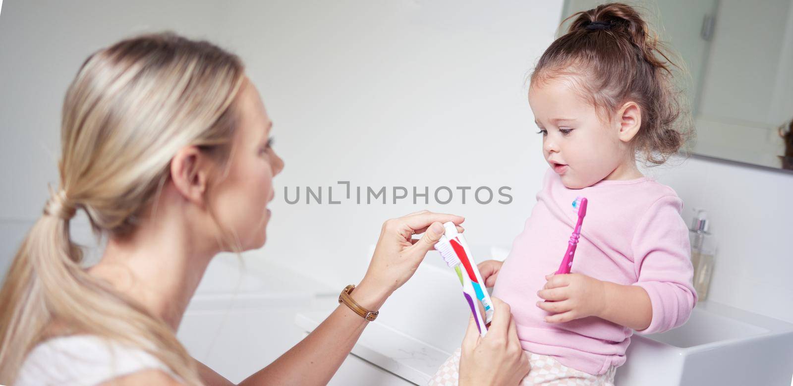 Baby kid brushing teeth with mom in bathroom, morning oral hygiene and clean dental healthcare wellness. Parent with toothpaste and toothbrush teaching young toddler girl child healthy mouth cleaning.