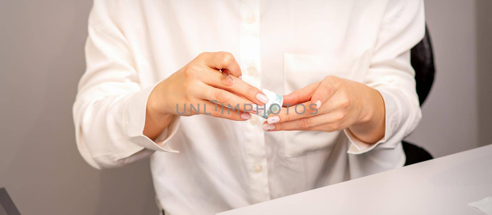 Manicure master's hands with beautiful manicure holding case box with nail sequins in nail salon