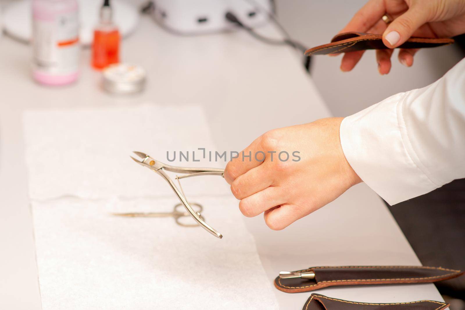 Nail nippers in the hand of female manicure master putting to the towel before nail care in manicure salon