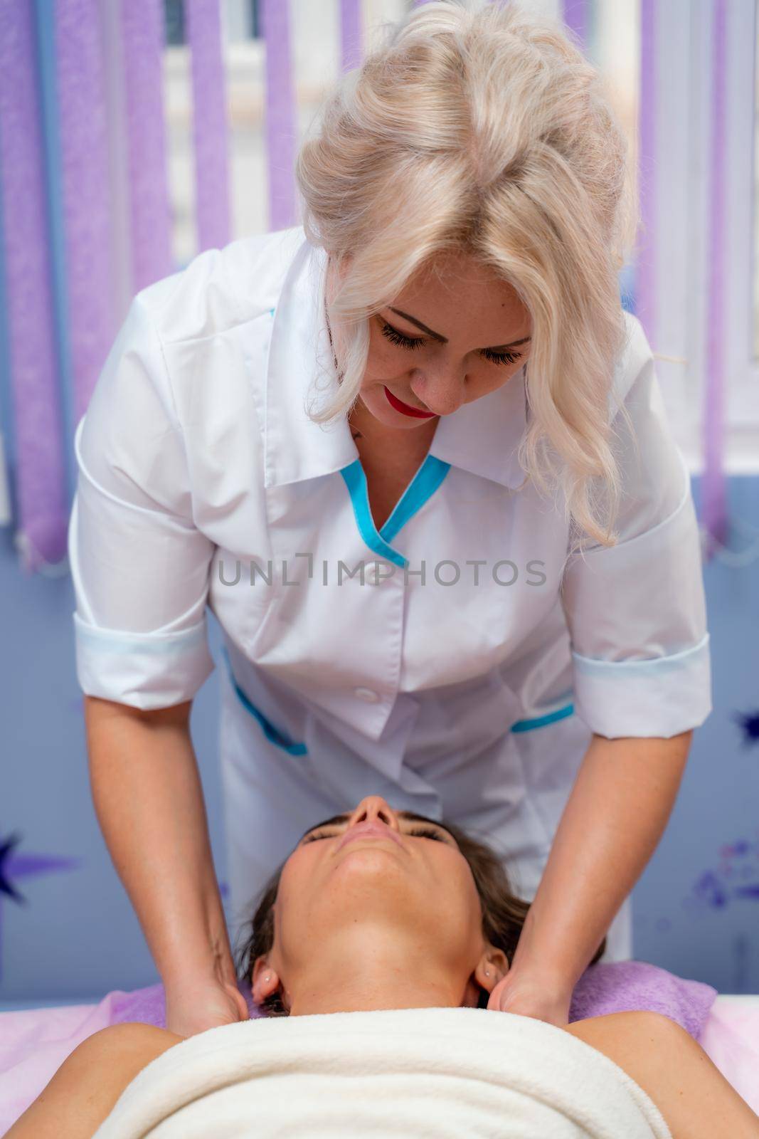 Masseur woman massages her shoulders. Woman getting a massage at the spa by Matiunina