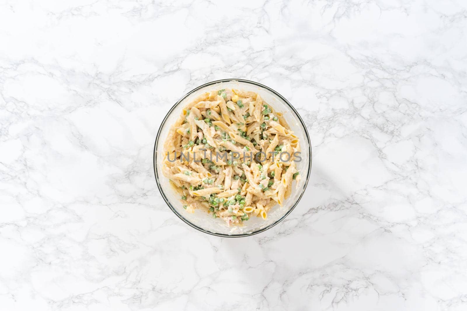 Flat lay. Mixing ingredients in a large glass mixing bowl to make macaroni salad with chicken.
