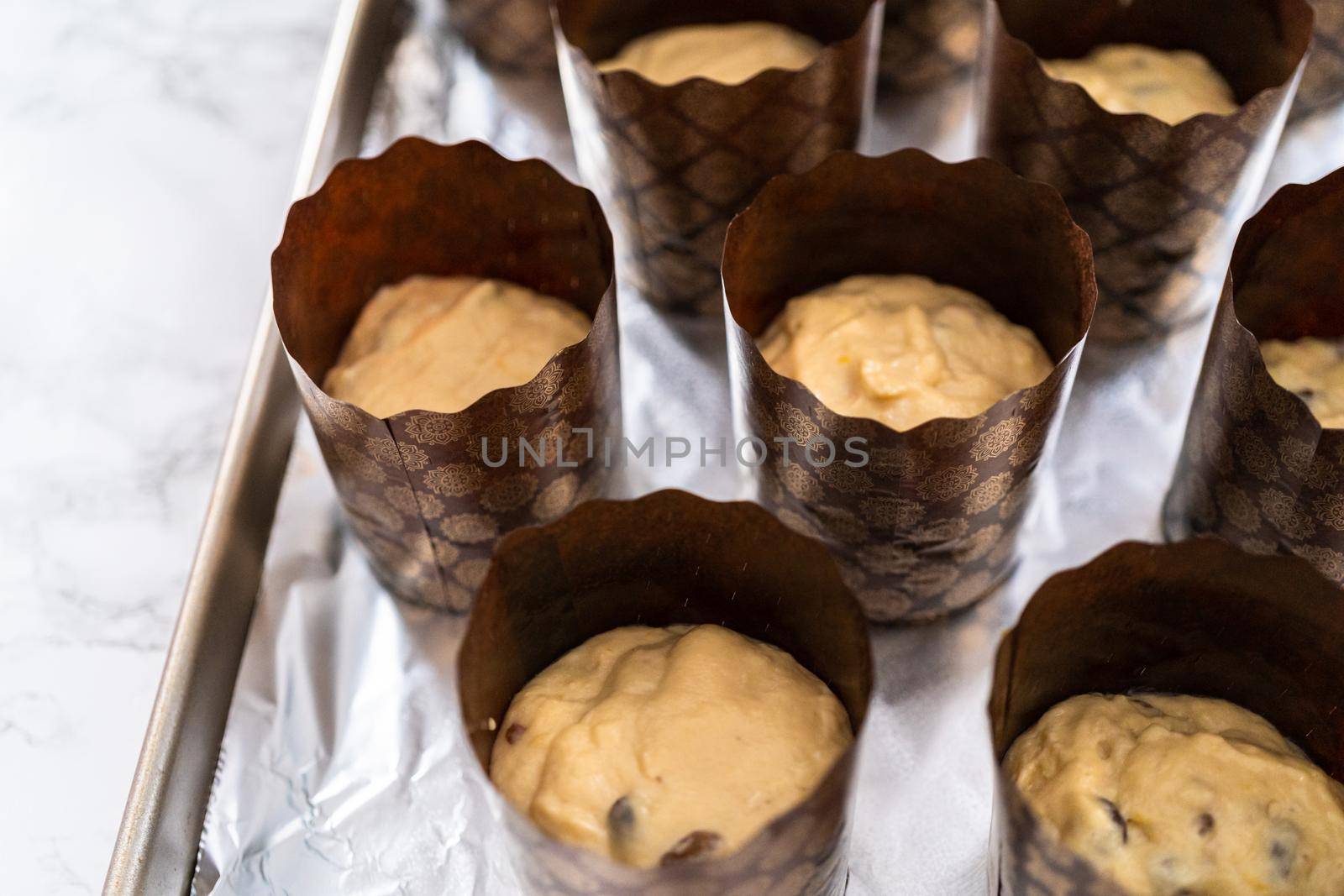 Rising dough in paper liners to bake mini Easter bread kulich.