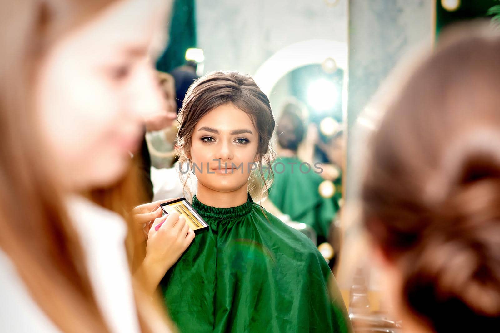 Make-up artist doing makeup for young beautiful bride applying wedding makeup in a beauty salon