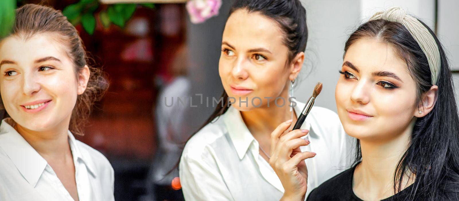 Make-up artist doing makeup for young beautiful bride applying wedding makeup in a beauty salon