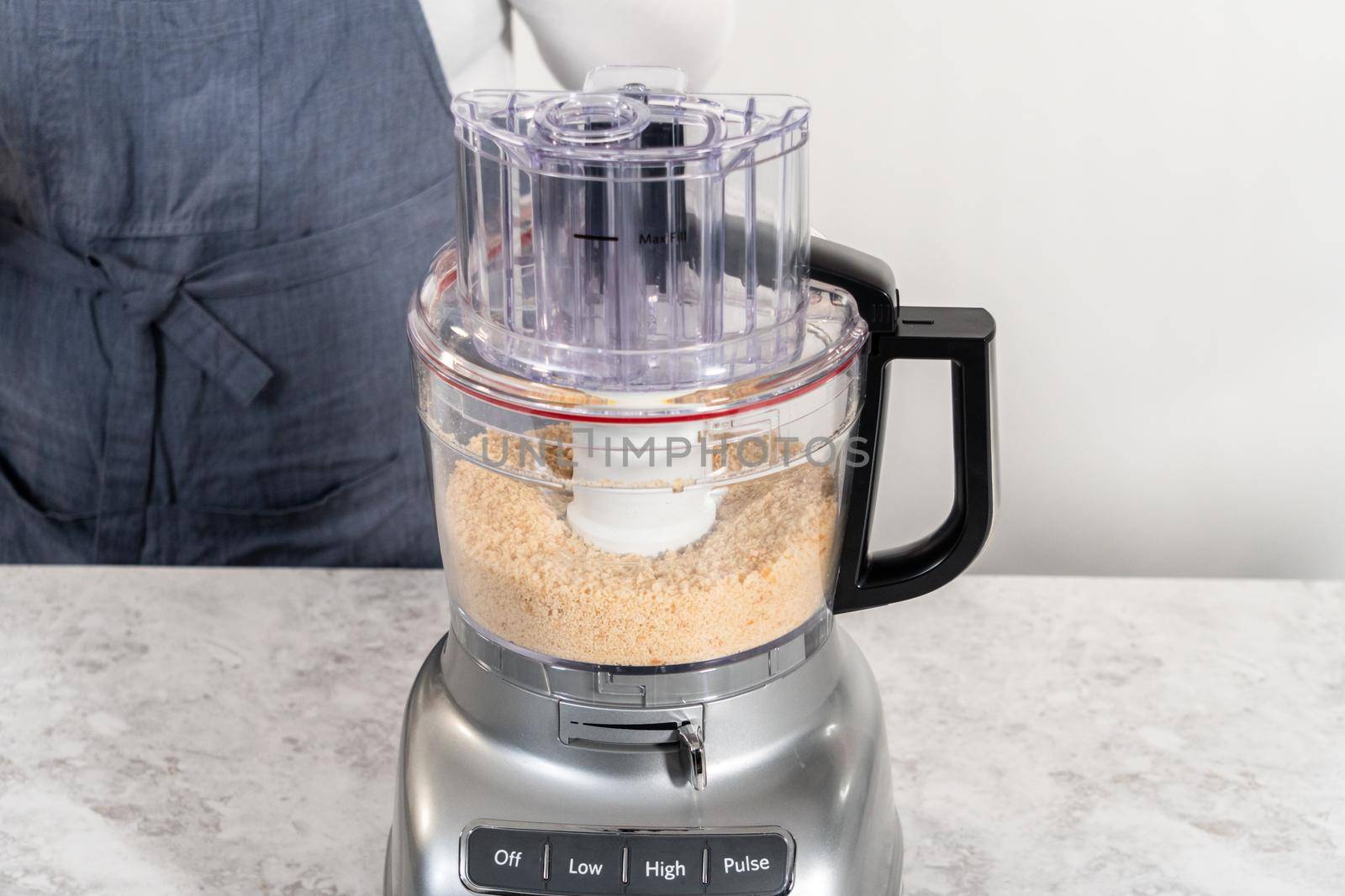 Crumbling stale bread in a food processor to make bread crumbs.