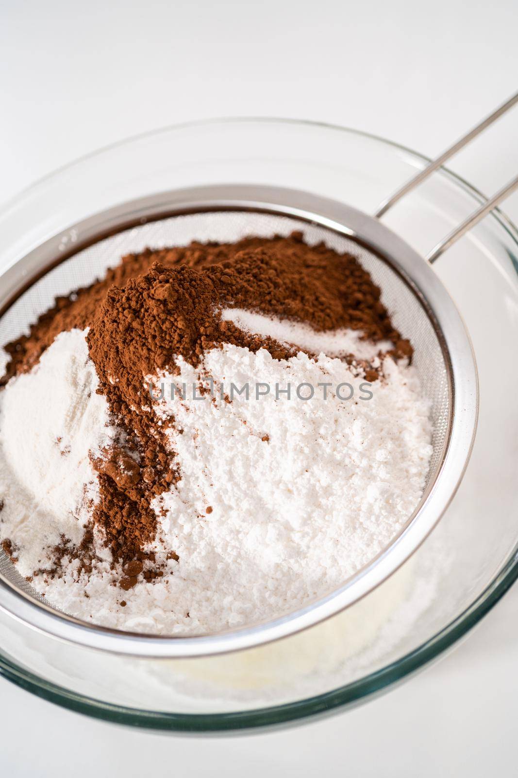 Sifting ingredients through hand sifter to make homemade hot chocolate mix.
