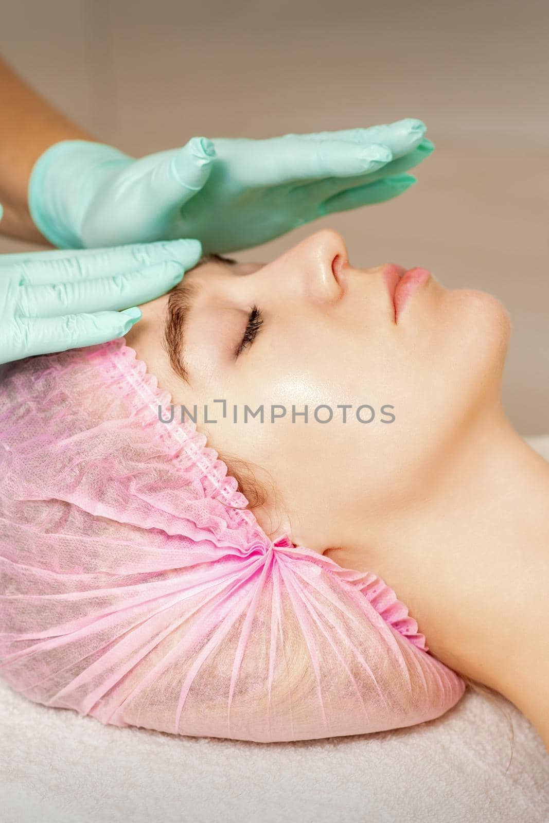 The woman is having cosmetic treatment during cosmetologist in medical gloves are touching the female face at the spa salon
