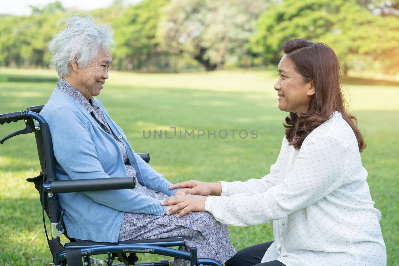 Caregiver help and care Asian senior or elderly old lady woman patient sitting on wheelchair in park, healthy strong medical concept. by pamai