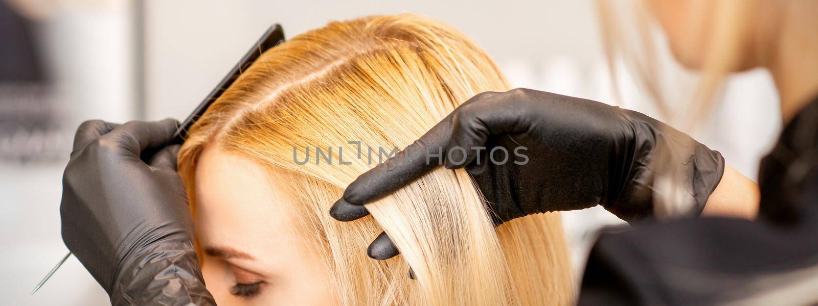 A hairdresser is combing female hairstyling in a hairdressing beauty salon. by okskukuruza