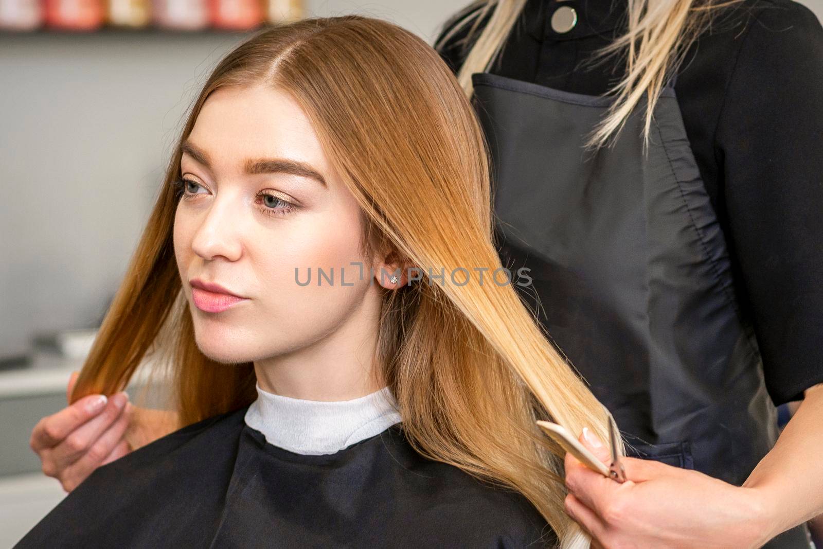 Hair stylist's hands doing professional hairstyling of female long hair in a beauty salon