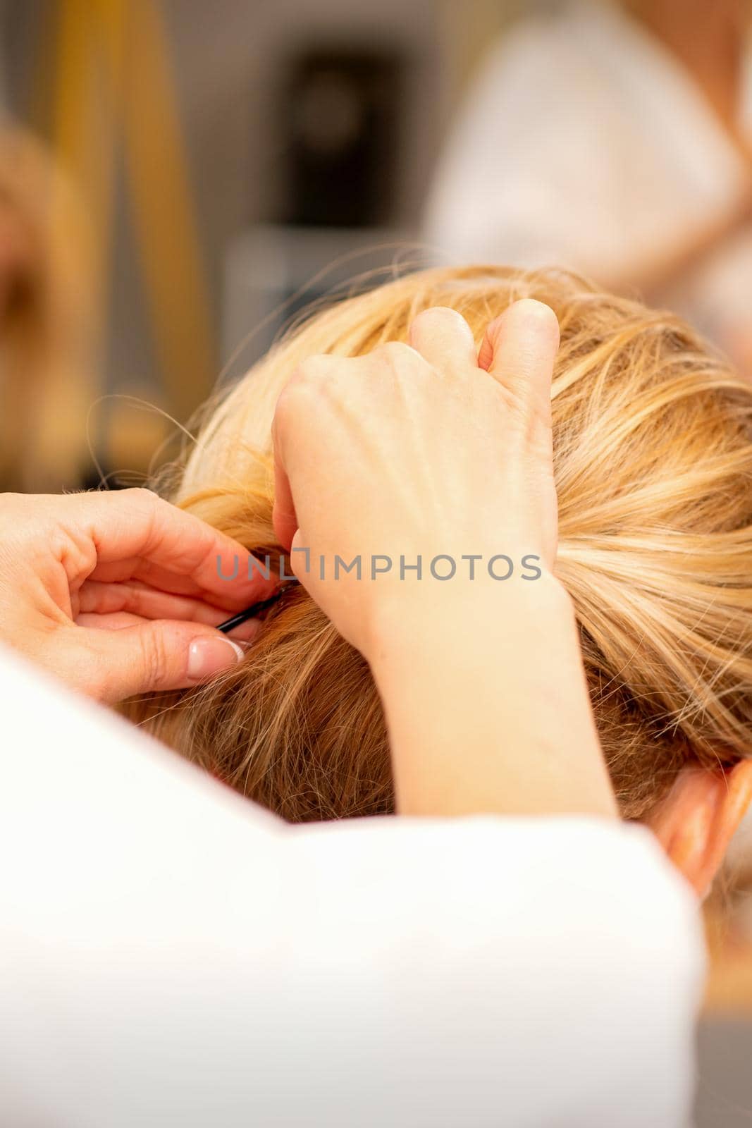 Hair stylist's hands doing professional hairstyling of female long hair in a beauty salon. by okskukuruza