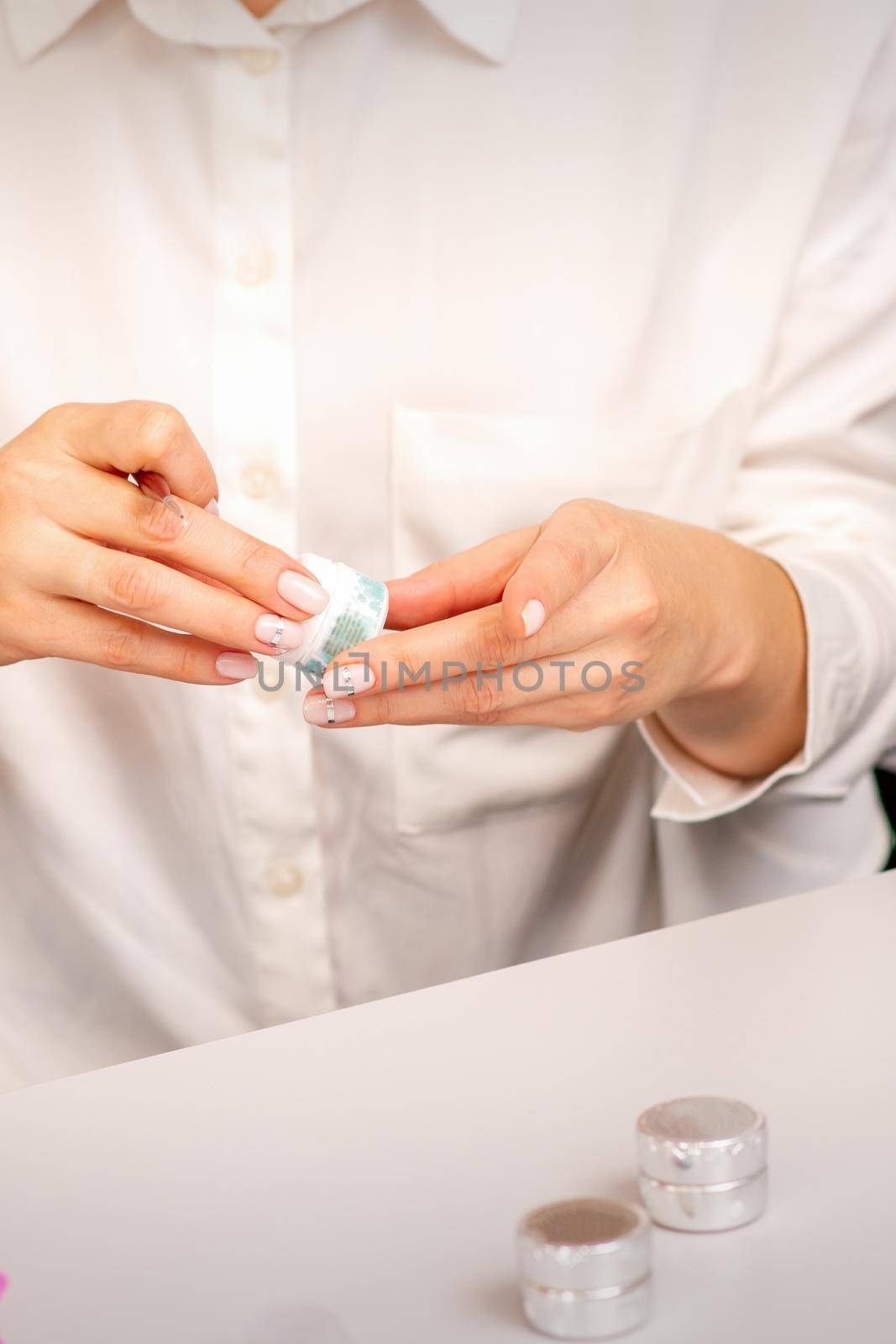 Manicure master's hands with beautiful manicure holding case box with nail sequins in nail salon