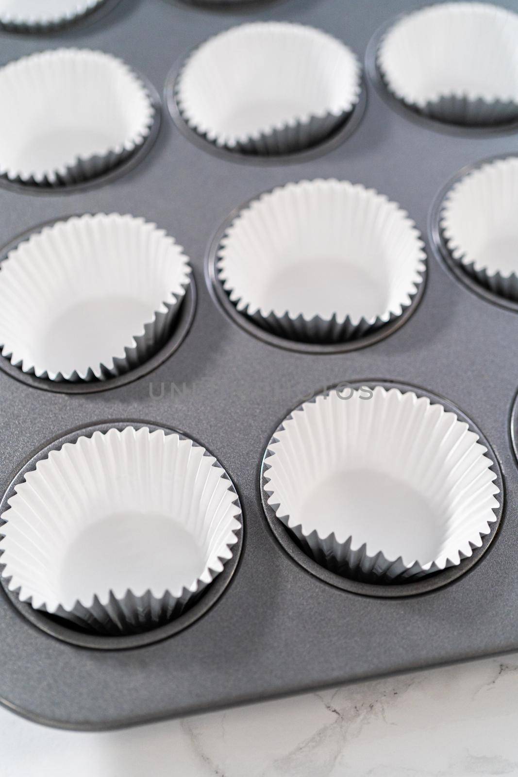 Lining baking cupcake pan with foil liners to bake lemon cupcakes.