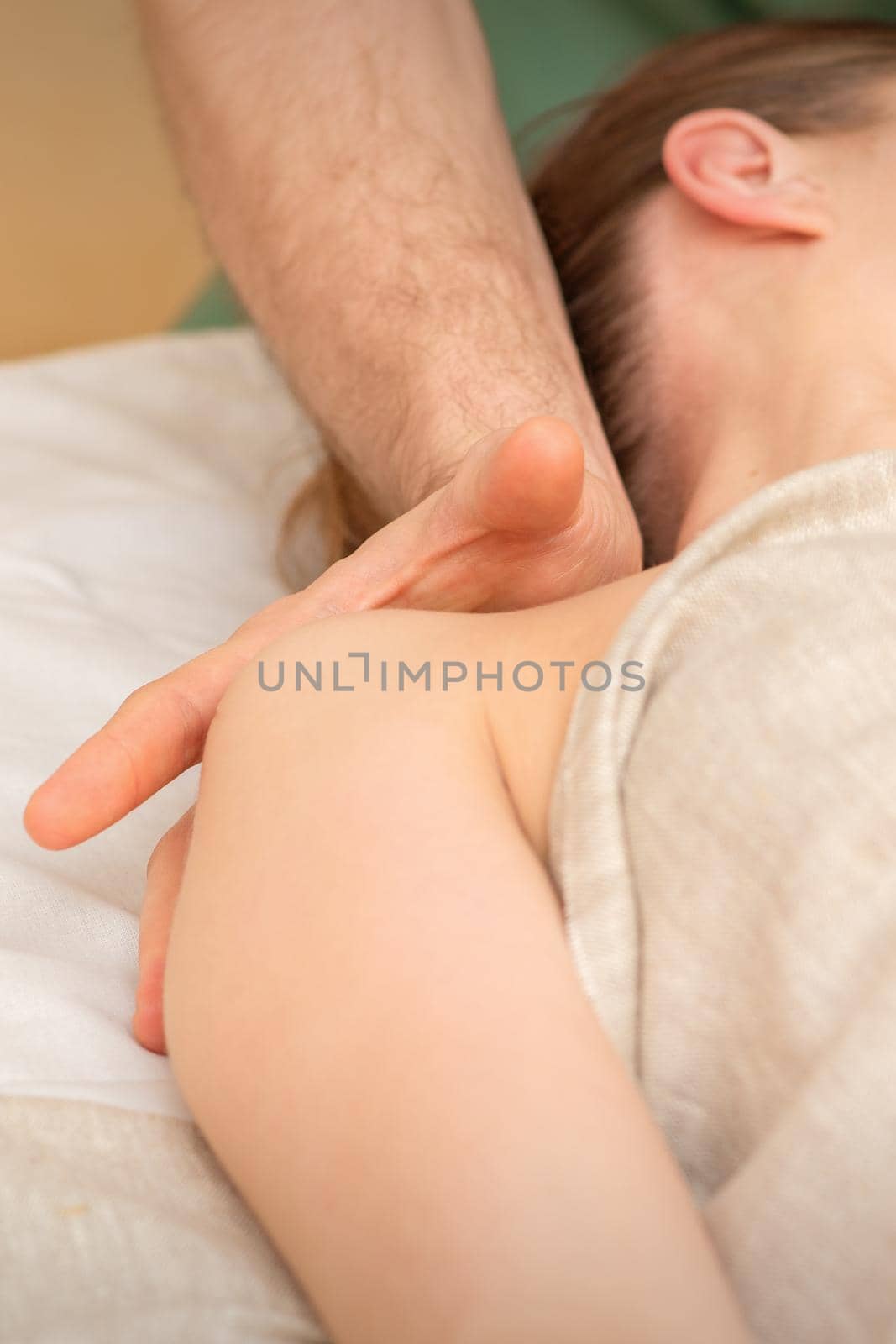 Young caucasian woman having a massage on the shoulder in spa salon. by okskukuruza