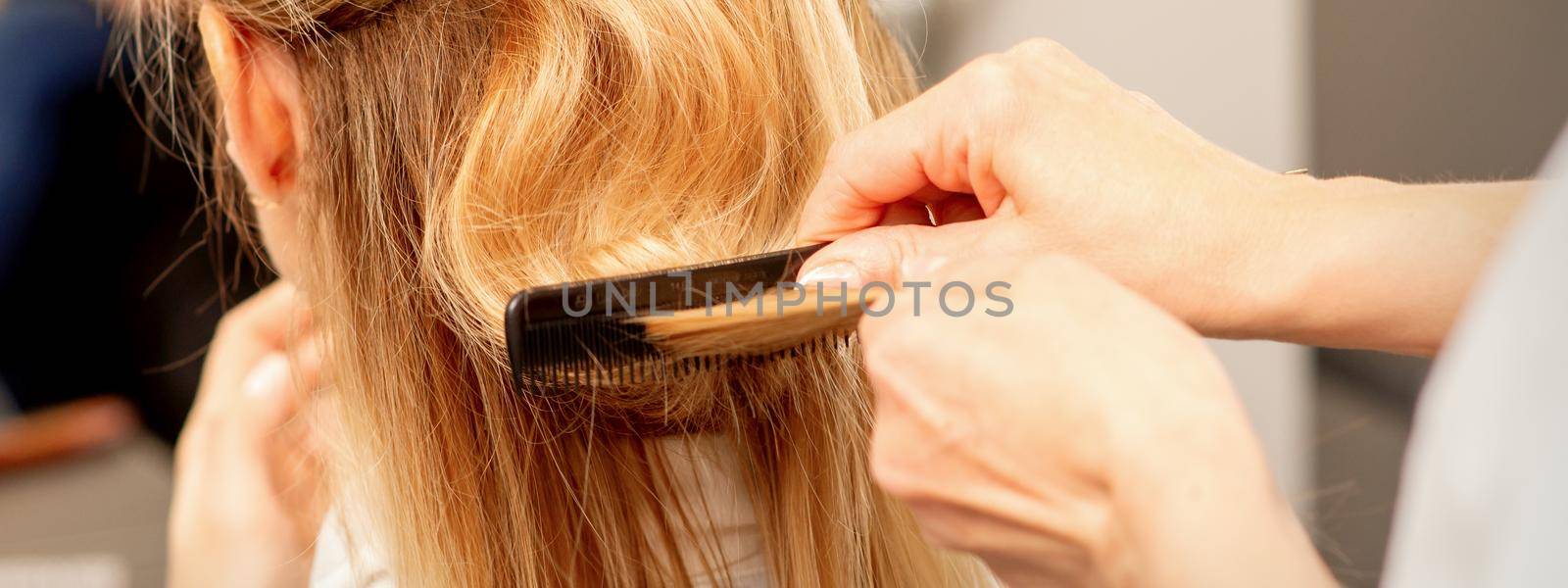 A hairdresser is combing female hairstyling in a hairdressing beauty salon. by okskukuruza