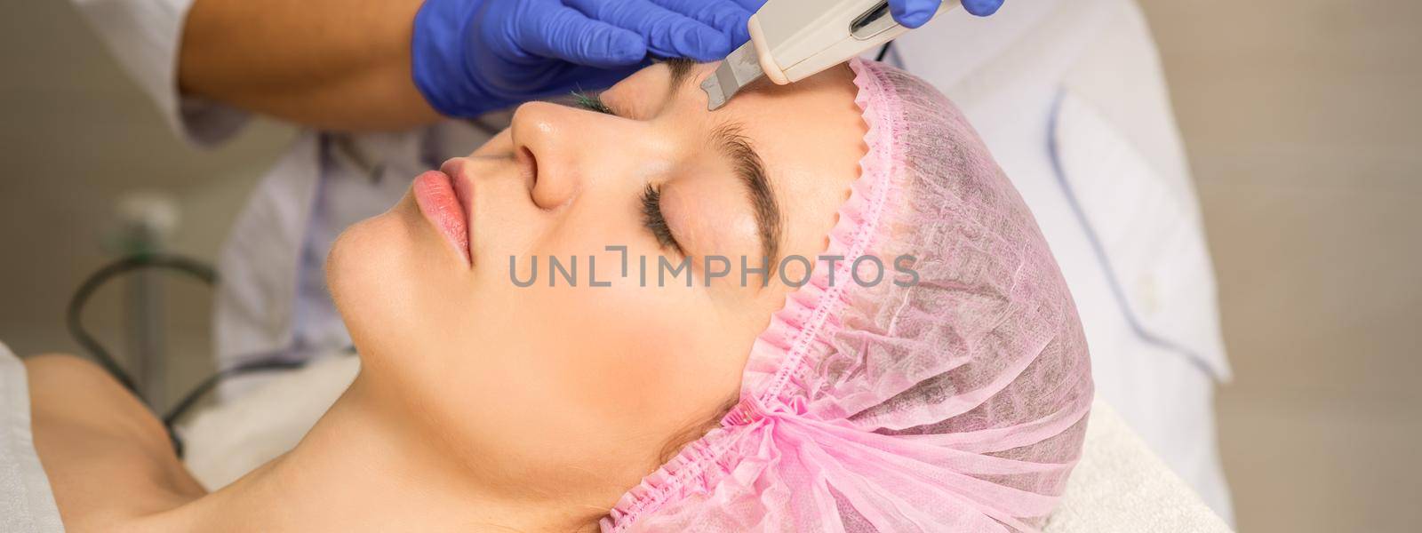 Young caucasian woman having ultrasonic peeling with ultrasound device in a cosmetic beauty salon. by okskukuruza