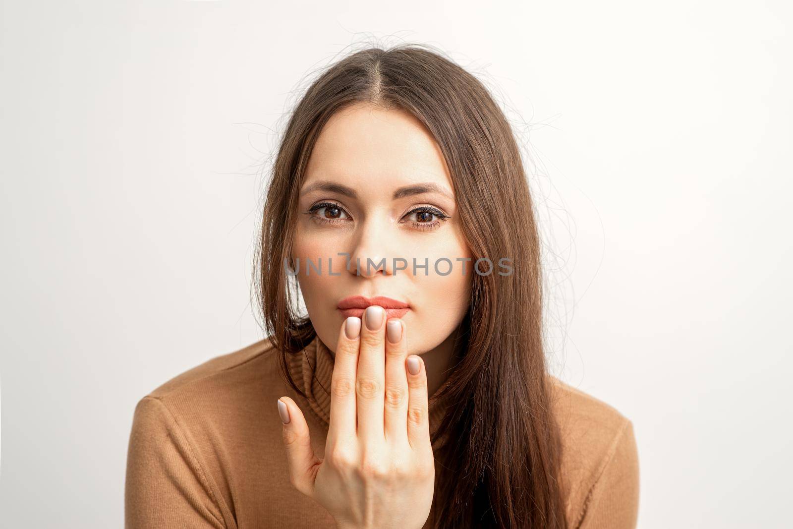 Young caucasian woman posing with fashion beige nails and sensual lips in studio