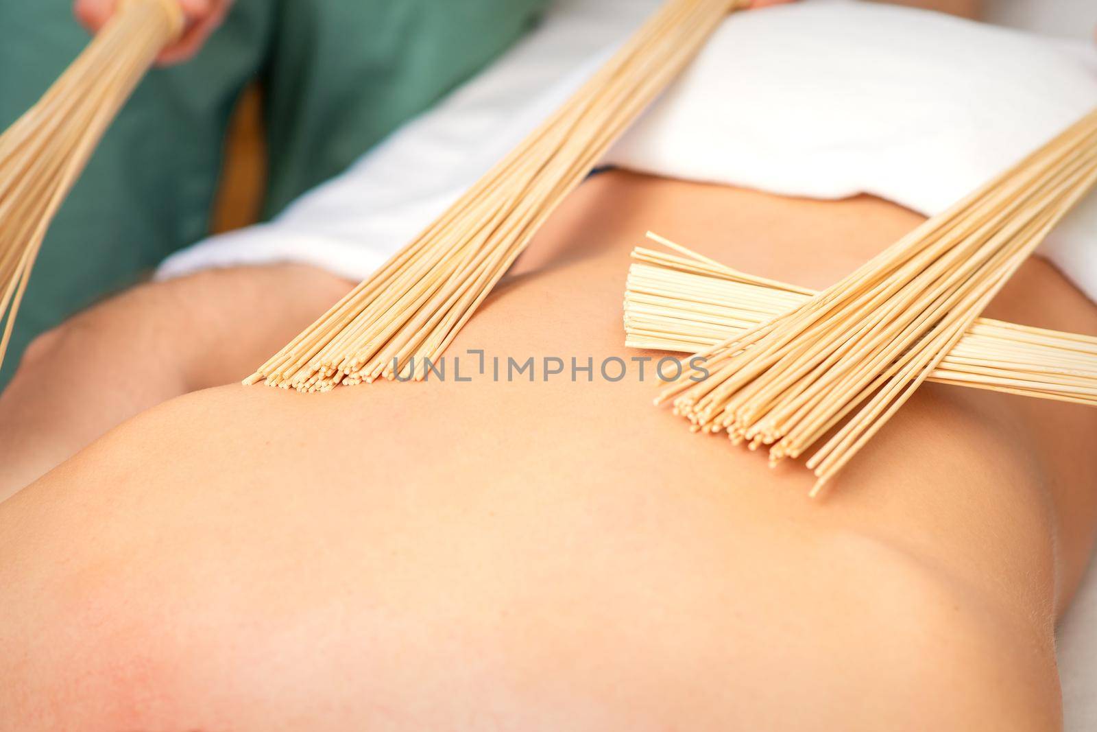 Young man have double samurai massage with bamboo brooms in spa. Relaxation massage concept