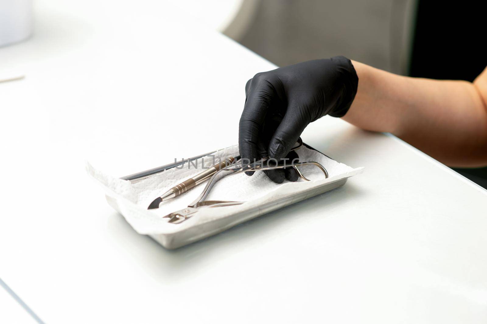 Professional manicure master prepares nail care tools on a white background with copy space