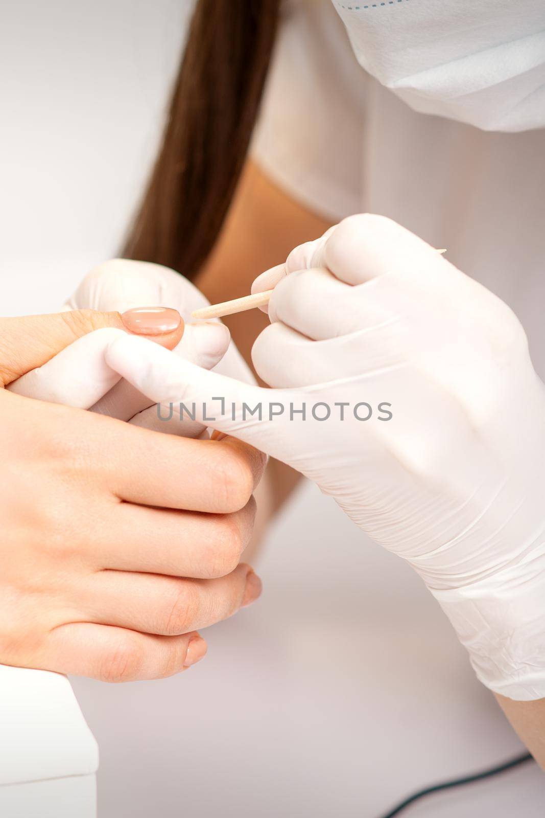 Young woman receiving pink or beige nail polish in a beauty salon. by okskukuruza