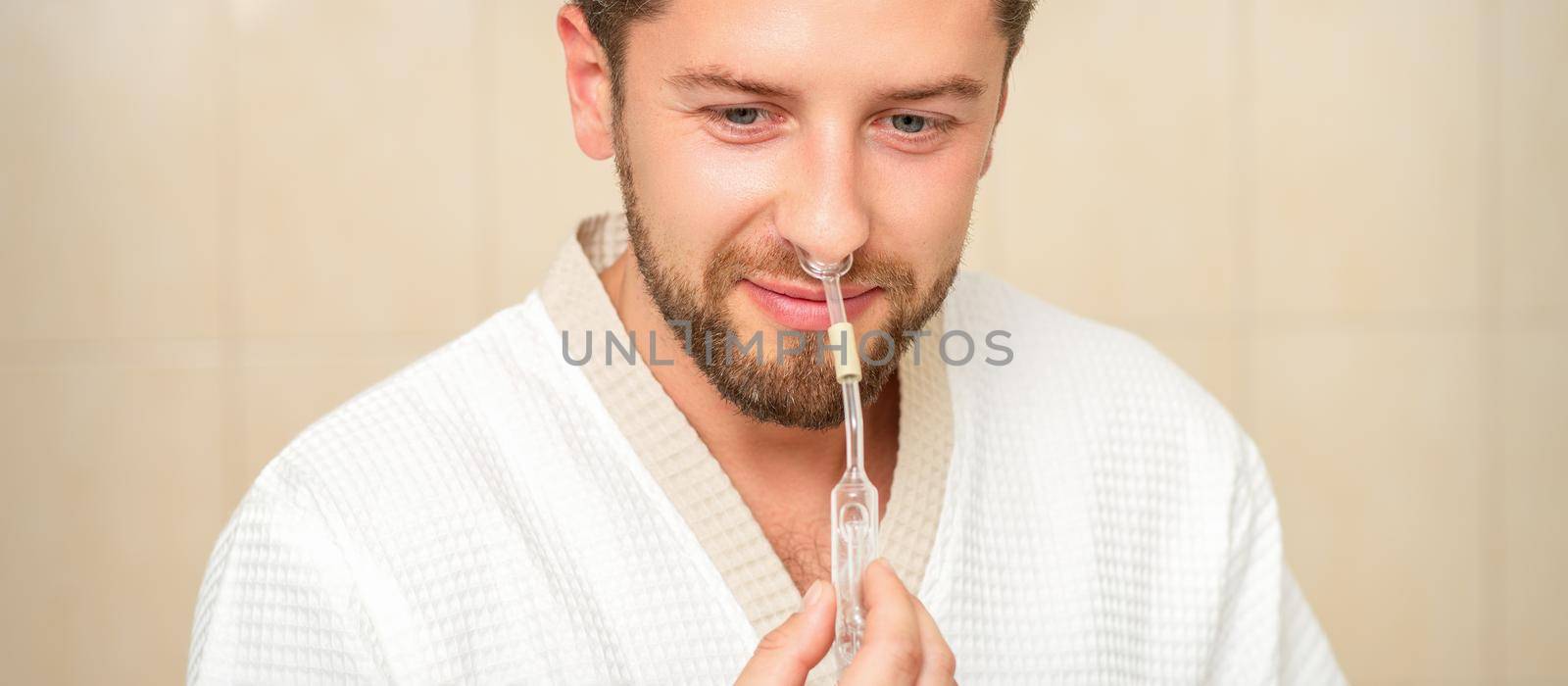 Young caucasian man receiving nasal inhalation Maholda with essential oil in the nose at a hospital. by okskukuruza