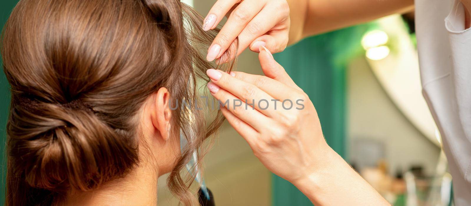 Close Up hairdresser stylist makes hairstyle for a young woman in a beauty salon. by okskukuruza