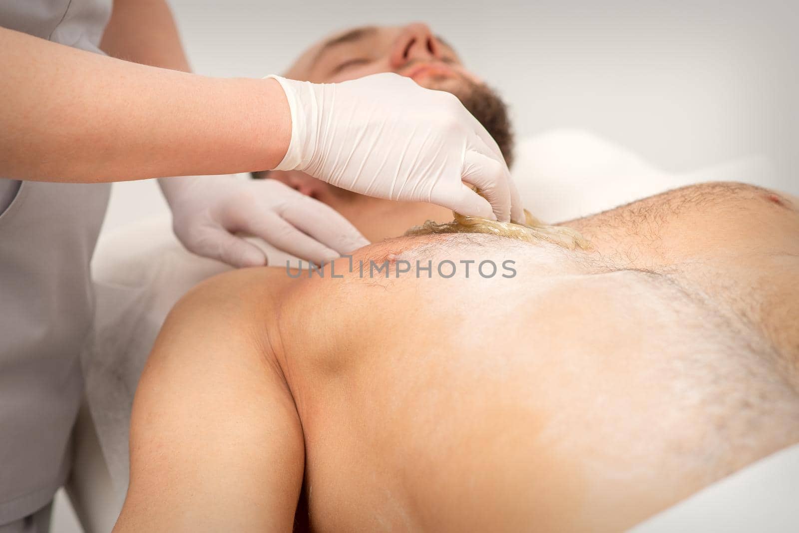 Epilation chest of a young male with the liquid wax paste in a beauty salon