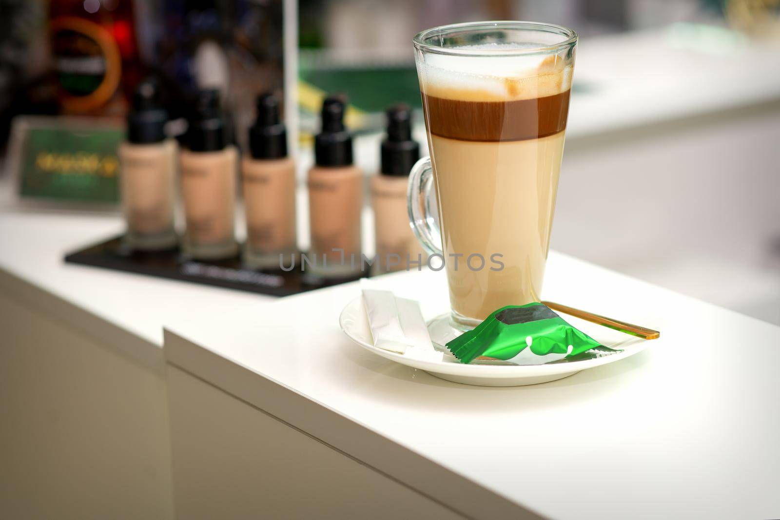 A cup of latte with candy on a saucer on the table in the manicure room. Manicure master place