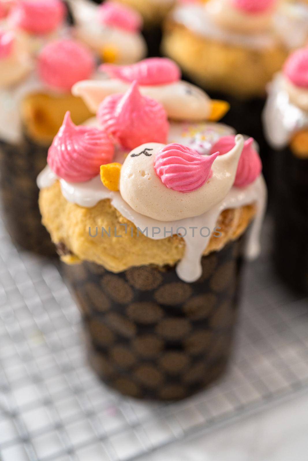 Decorating mini Easter bread kulich with sprinkles and meringue bird-shaped cookies.