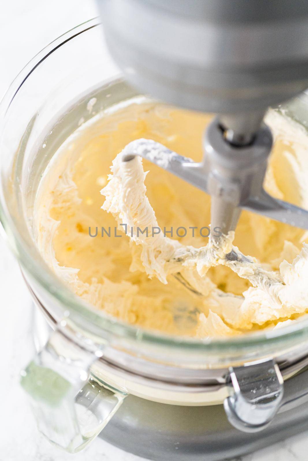 Mixing ingredients in kitchen electric mixer to make lemon buttercream frosting.