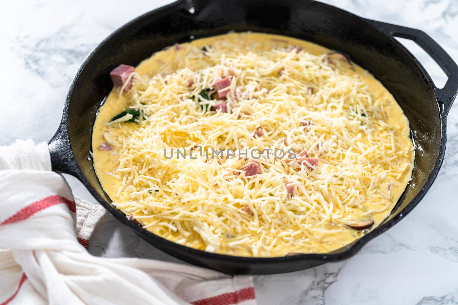 Preparing spinach and ham frittata in cast iron skillet.