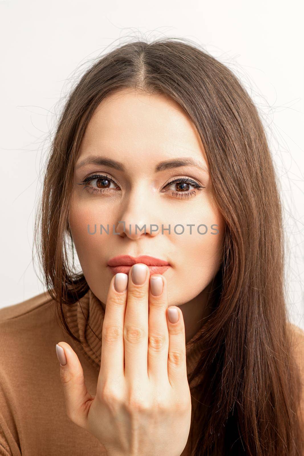 Young caucasian woman posing with fashion beige nails and sensual lips in studio. by okskukuruza