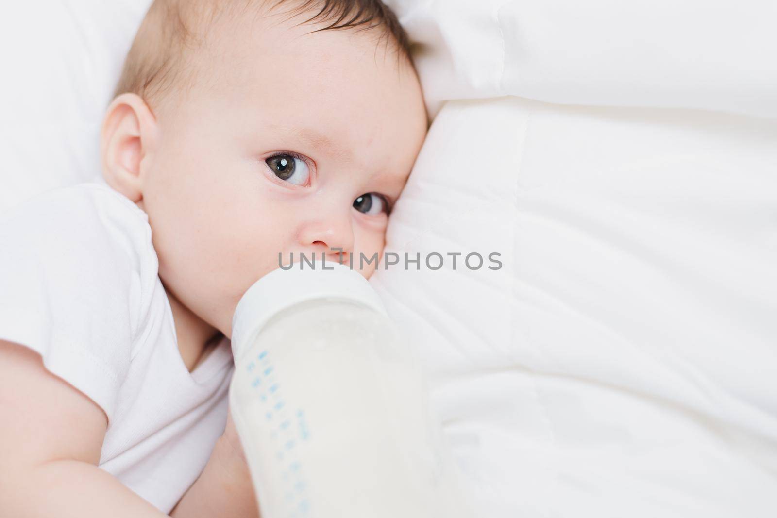 The baby in his crib eats from a bottle . Baby food copyspace . Artificial feeding. by alenka2194